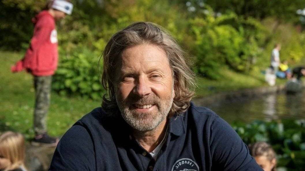 Erik Berglihn med barn langs sjøkanten  i bakgrunnen 