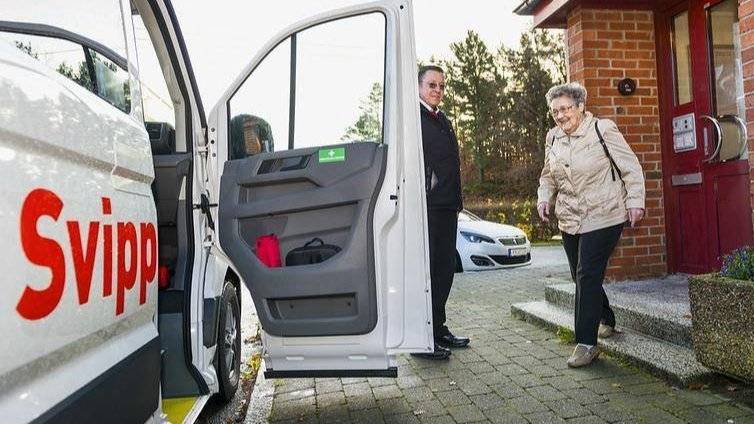Kvinne på vei inn i en AKT Svipp-bil. Sjåfør holder døren åpen.