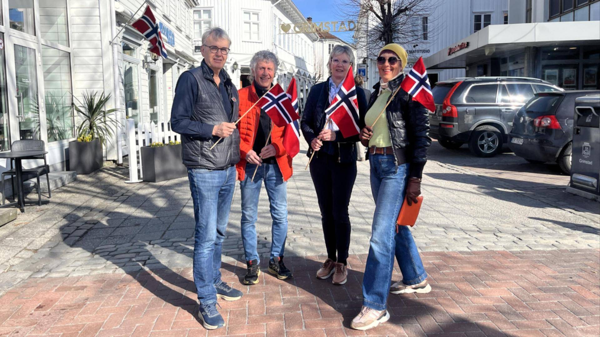 Bilde av  medlemmer i 17. maikomiteen som holder norske flagg.